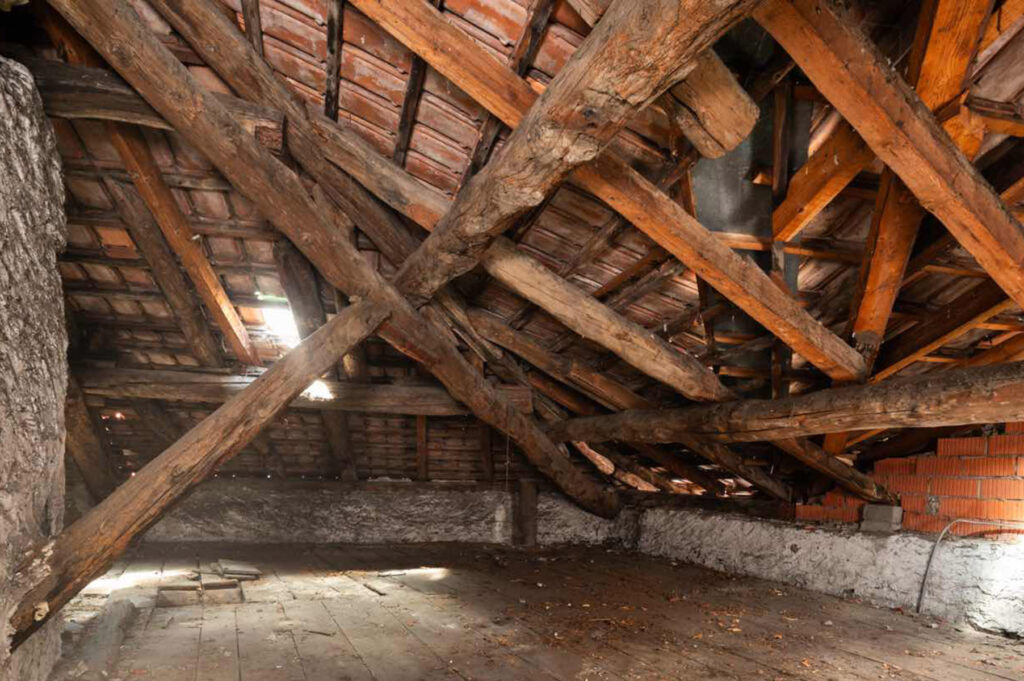 Sottotetto di Casa Varenna a Locarno prima del restauro, con antica struttura portante in legno, travi incrociate e copertura in coppi.