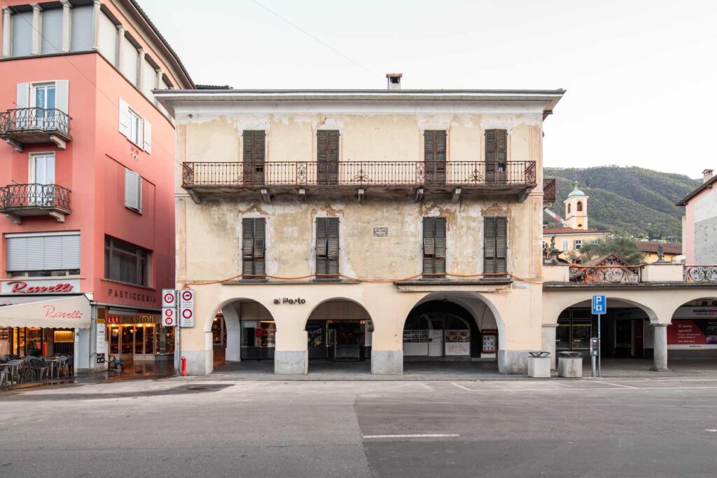 Facciata sud di Casa Varenna a Locarno prima del restauro, con portici al piano terra, balcone in ferro battuto e intonaci storici deteriorati.