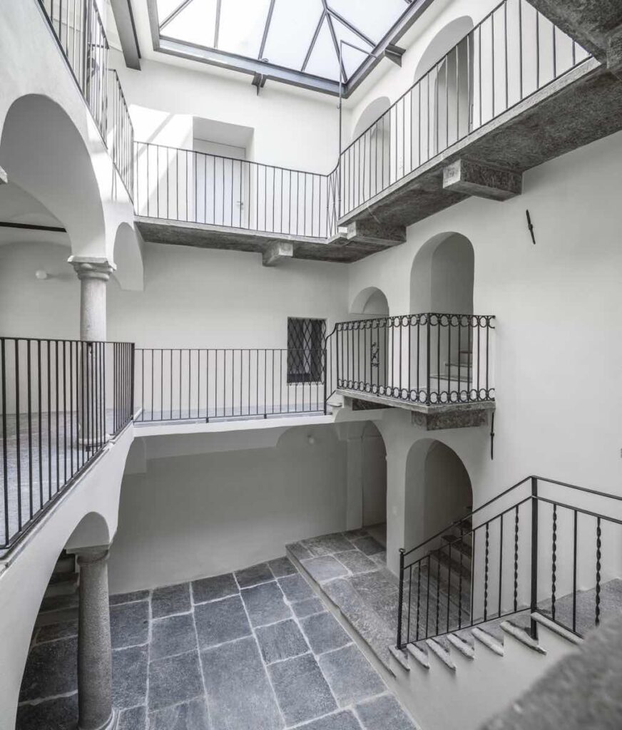Corte interna di Casa Varenna a Locarno dopo il restauro, con porticati ad arco, ballatoi e copertura vetrata.