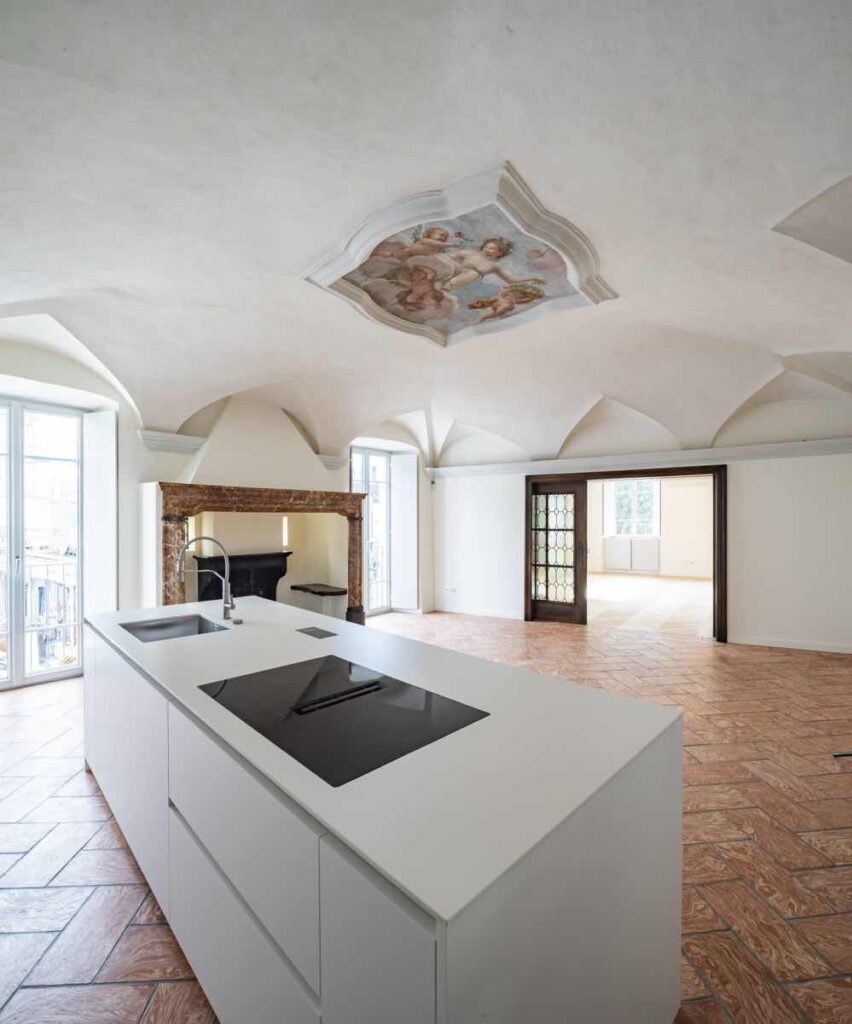 Casa Varenna a Locarno: salone restaurato con camino, volte e medaglione settecentesco affrescato dalla bottega degli Orelli, con cucina contemporanea.