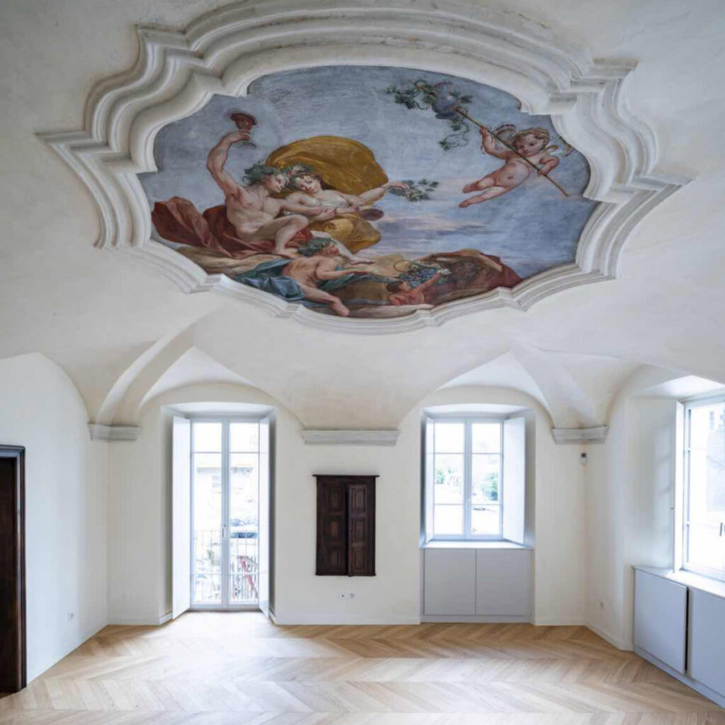 Salone restaurato di Casa Varenna a Locarno, con medaglione settecentesco affrescato dalla bottega degli Orelli, volte storiche e pavimento in legno.