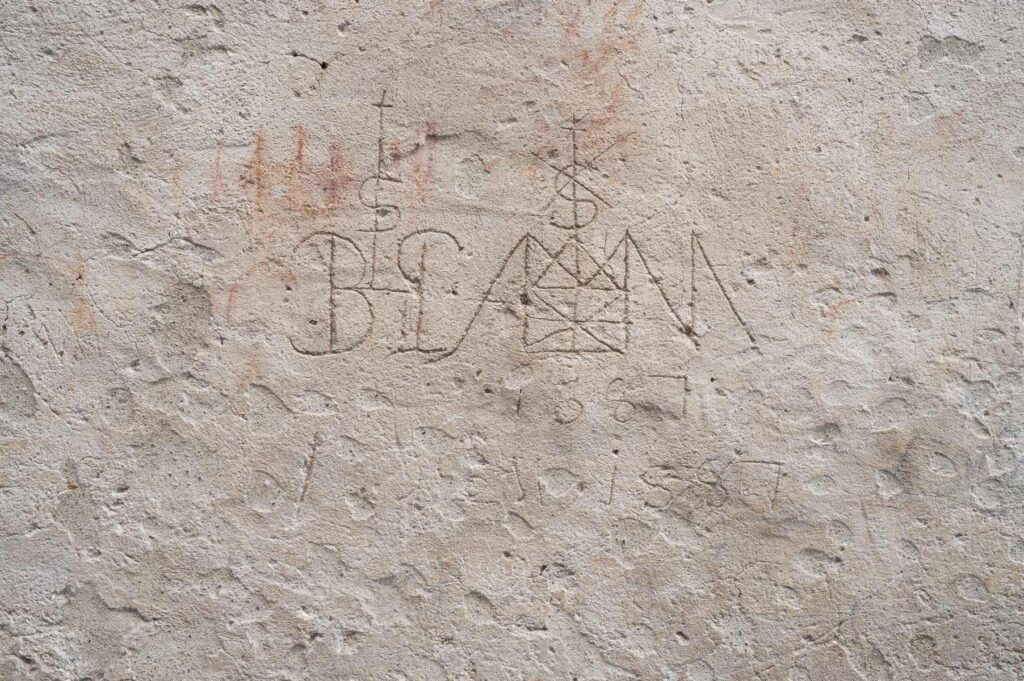 Dettaglio delle antiche incisioni e iscrizioni sull'intonaco storico di Casa Varenna a Locarno, conservate durante il restauro.